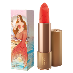 Red lipstick with gold cap and mermaid-themed packaging on a white background