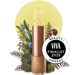 A colorless lip balm stick with the Karen Murrell brand logo, displayed against a backdrop with floral elements and a 'VIVA Finalist 2025 Beauty Awards' seal.
